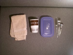 kleines Handtuch, Keramik-Kaffeebecher, Plastikdose, Messer, Gabel, Löffel